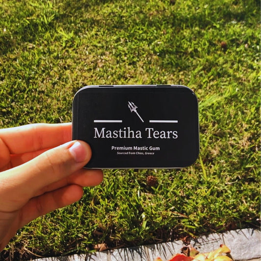 Mastiha Tears Black Hinged Tin held by hand with grass background